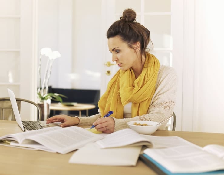 Young university student using laptop and books in studying at home